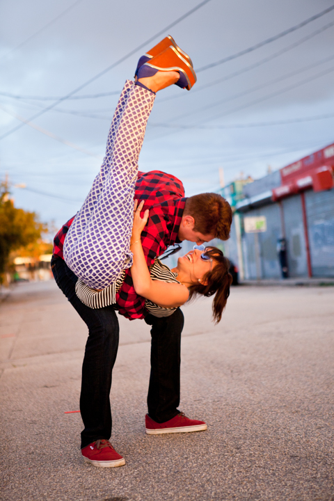 Two adults perform a playful balancing pose with one person held upside down.