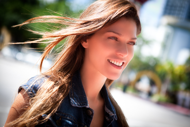 A smiling woman turns toward the camera as the wind lifts her hair.