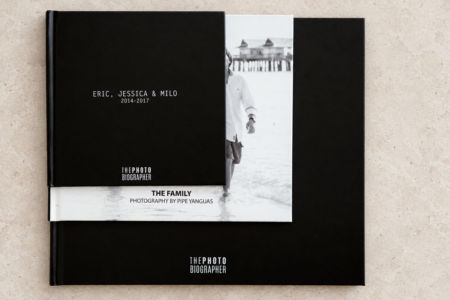 PHOTObiography books in different sizes are arranged on a pale stone surface.
